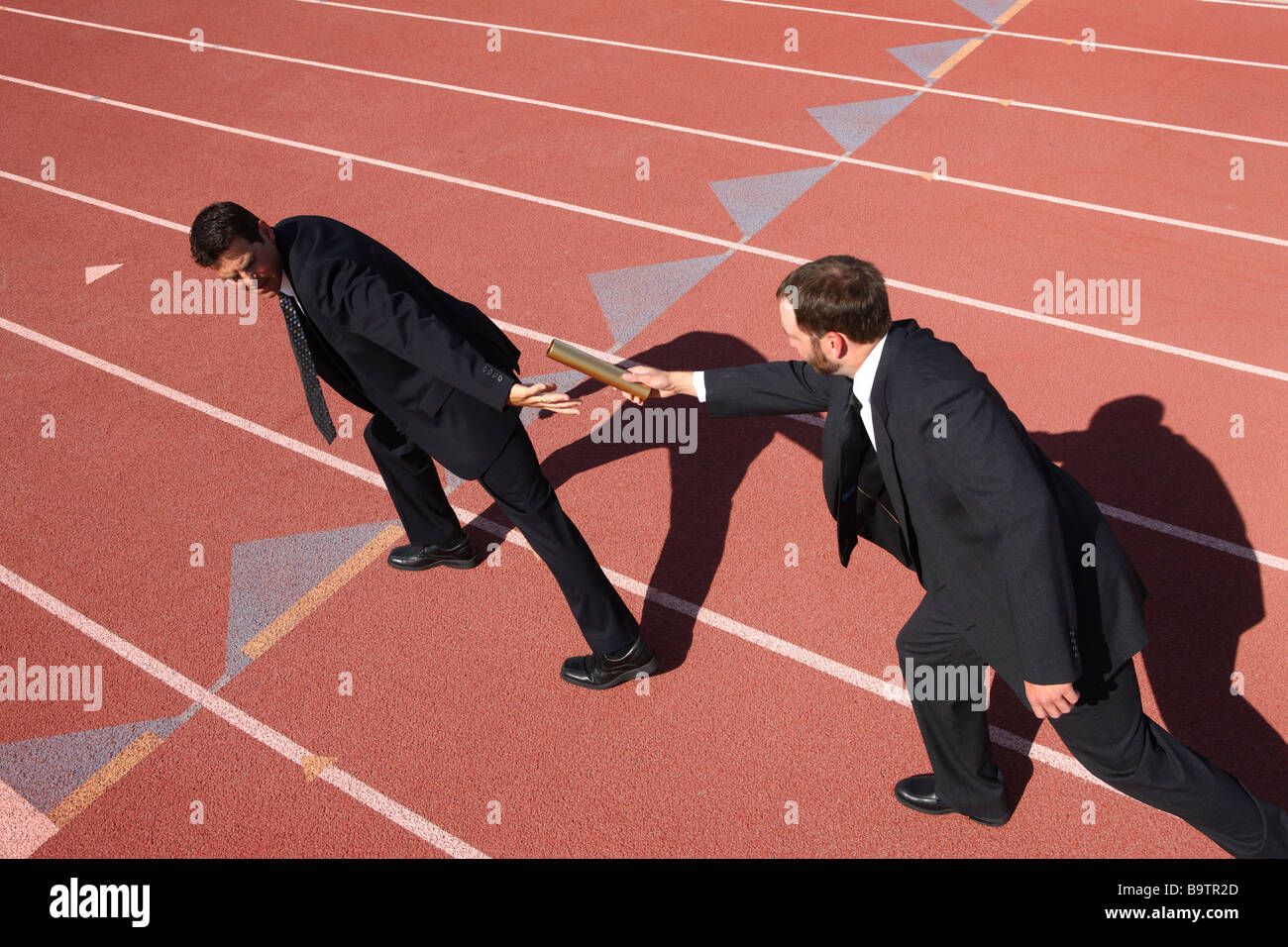 Businessmen hand baton in track race Stock Photo Alamy