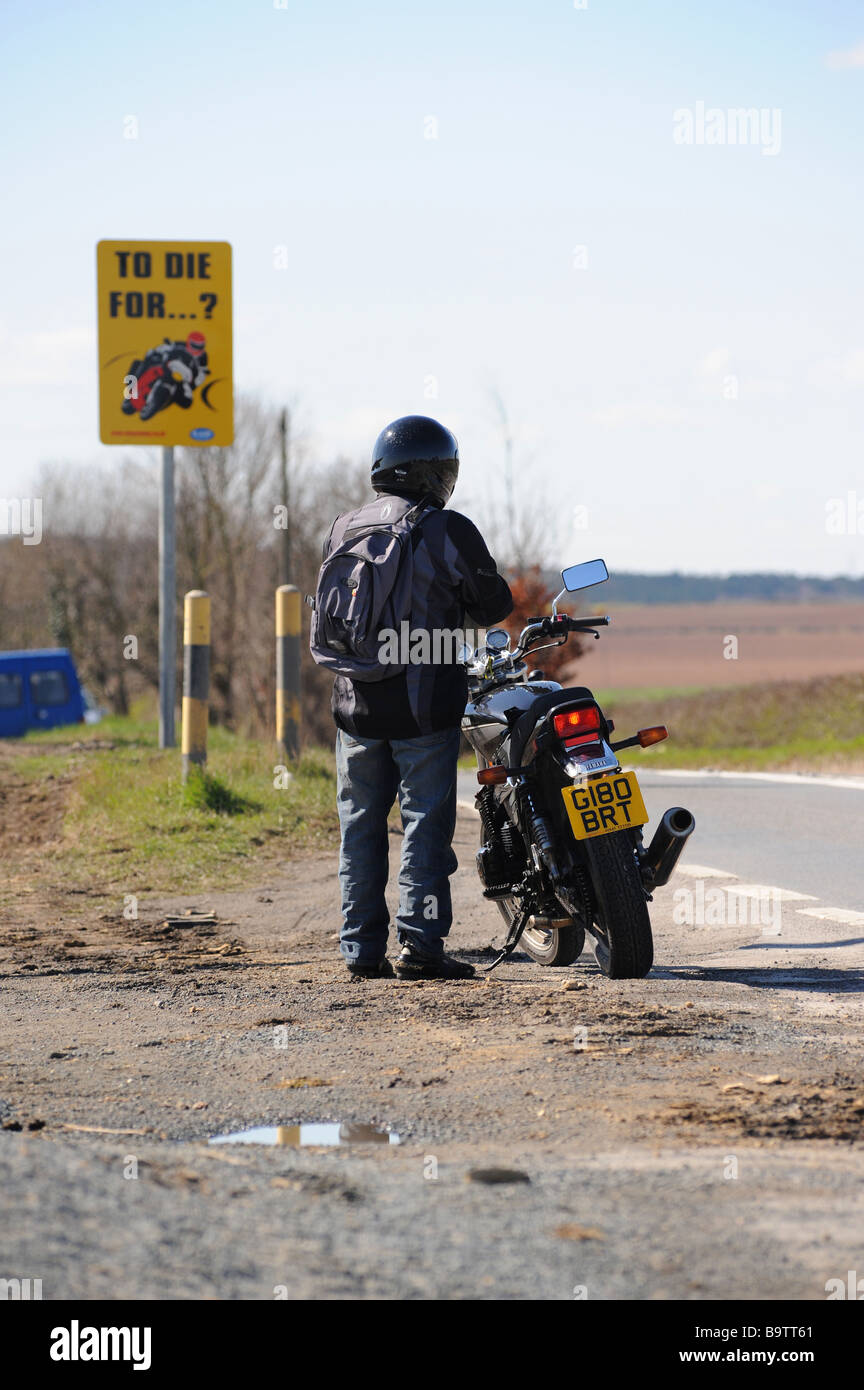 Motorbike rider in front of warning sign Stock Photo