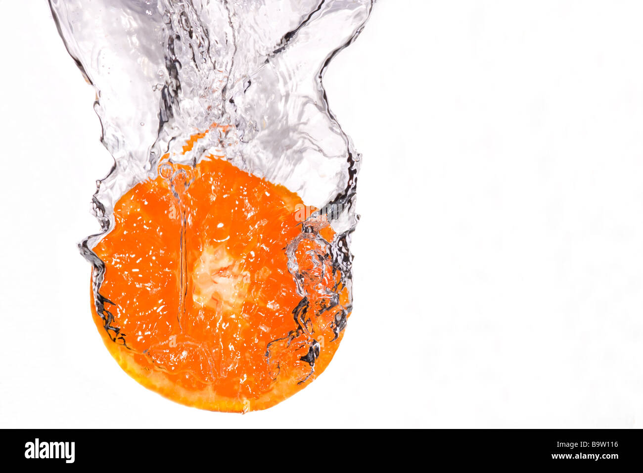 Orange slice splashing in to water on white background Stock Photo - Alamy