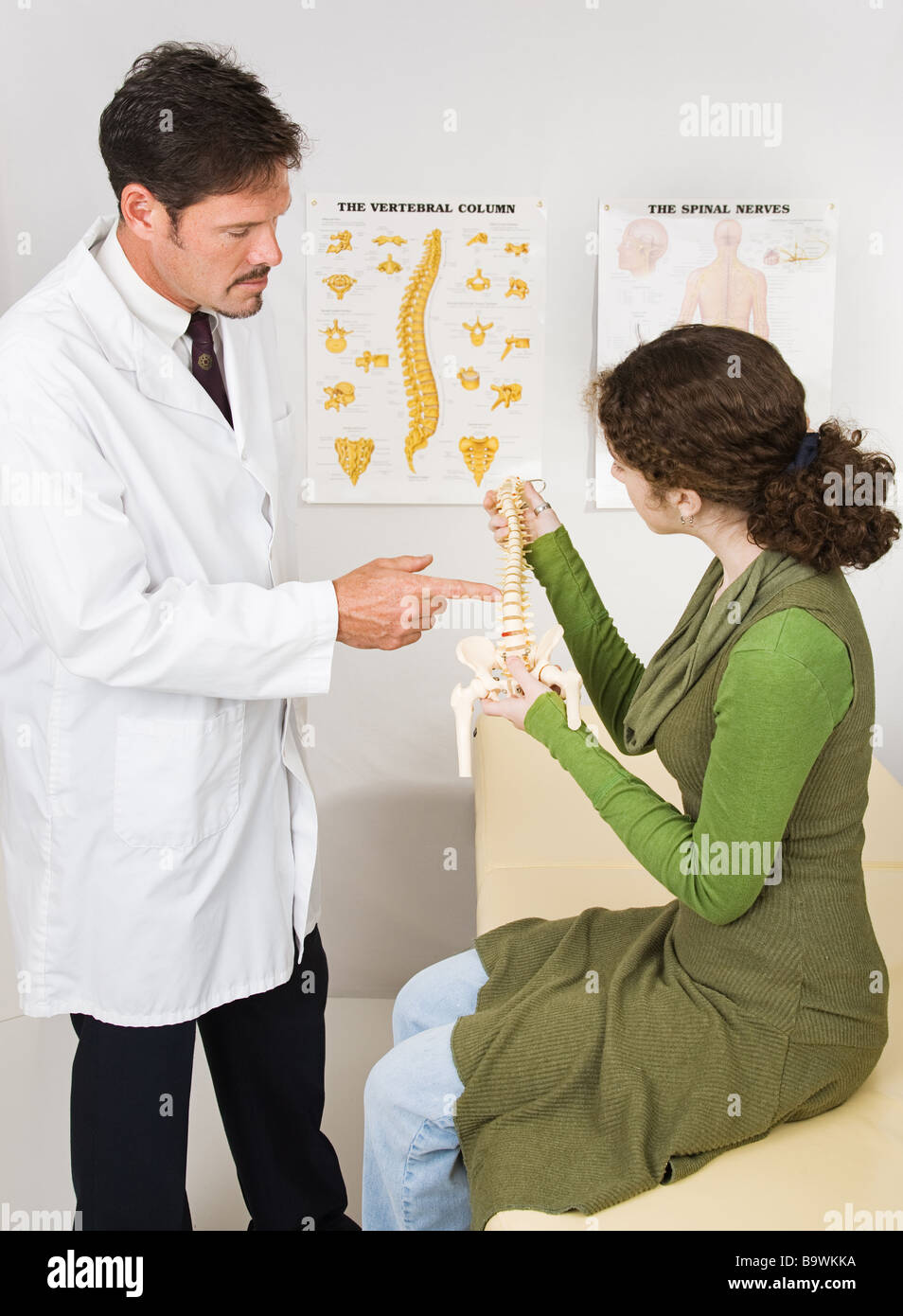 Chiropractor uses model of the spine to explain chiropractic to a