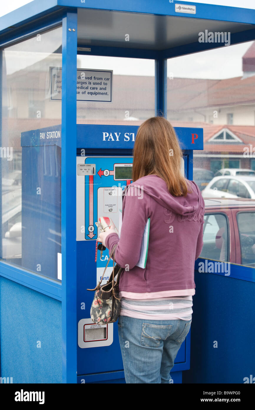 A female uses an automated kiosk to pay a parking charge to park in the car park of a UK hospital Stock Photo