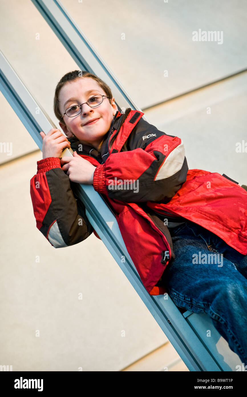 boy in a red jacket climbing a pair of poles Stock Photo