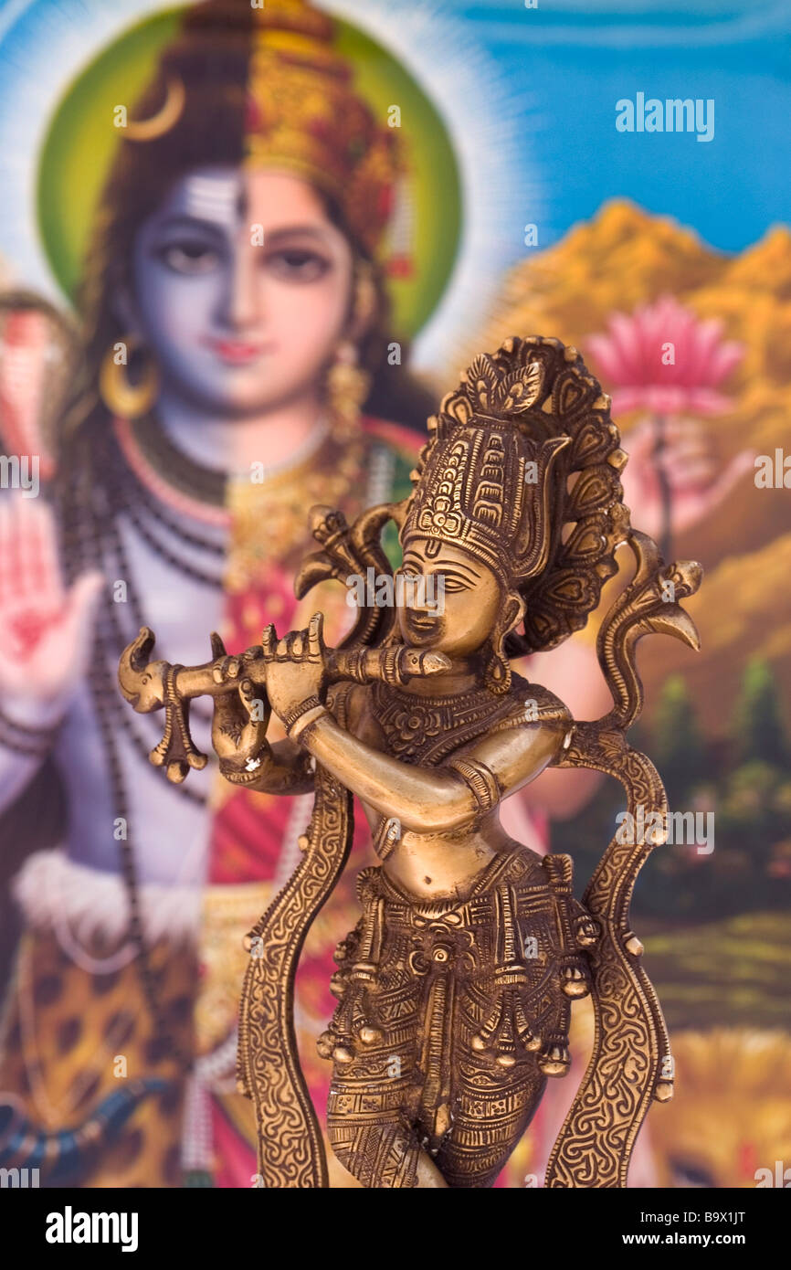 Brass Statue of Indian (Hindu) God Krishna playing the Flute with colourful Indian background Stock Photo