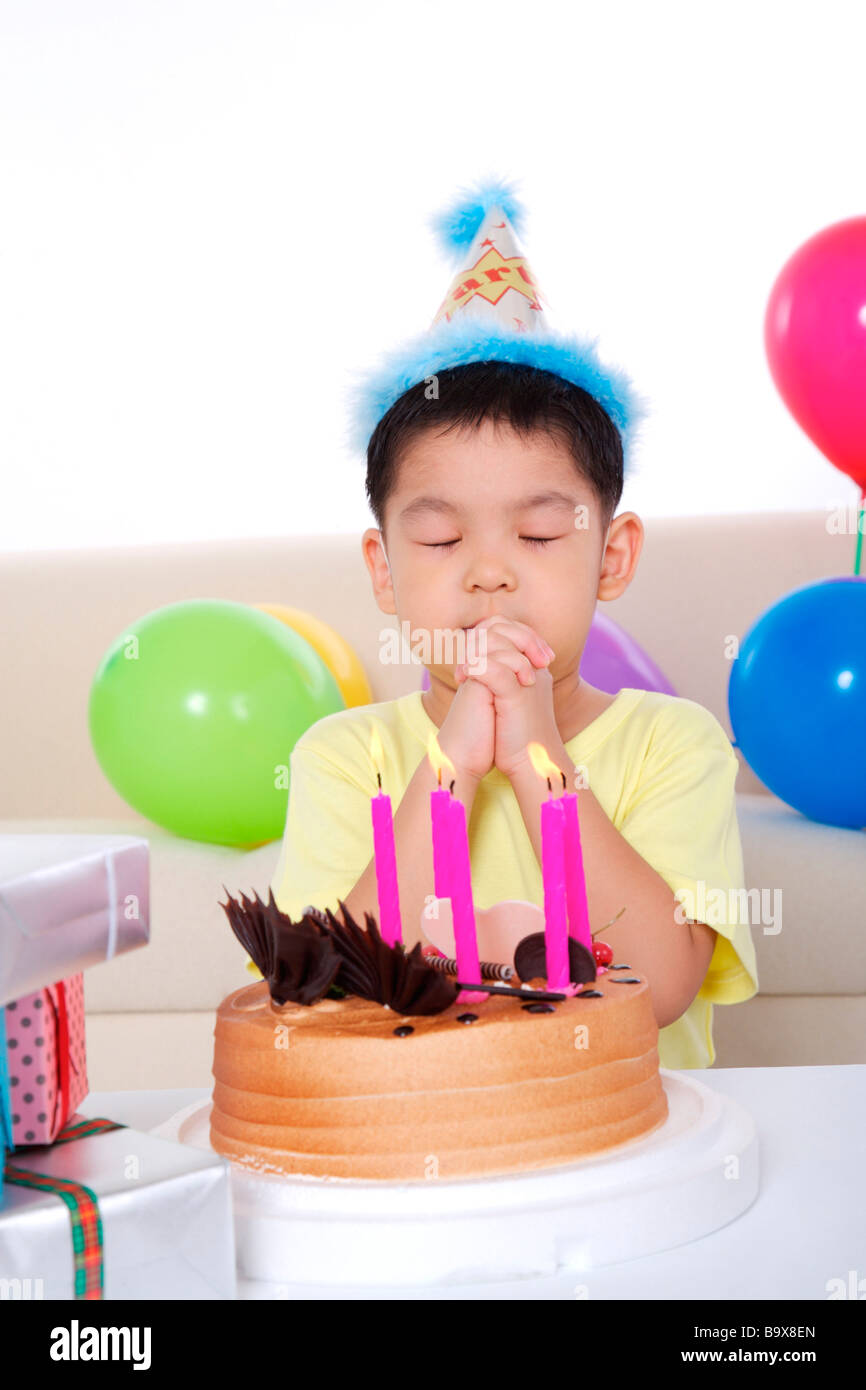 Boy making wish in front of birthday cake Stock Photo - Alamy