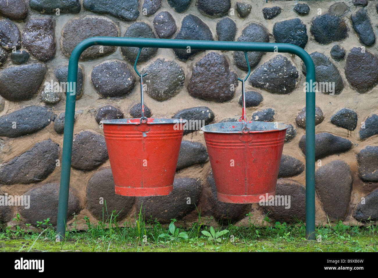 Red fire buckets hanging outside a cottage in the Injisuthi National Park in the Drakensberg mountains. Kwazulu Natal, South Africa Stock Photo