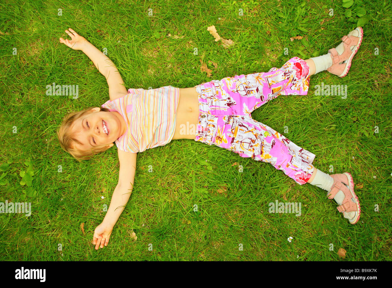smiling little girl lies on back on grass Stock Photo - Alamy