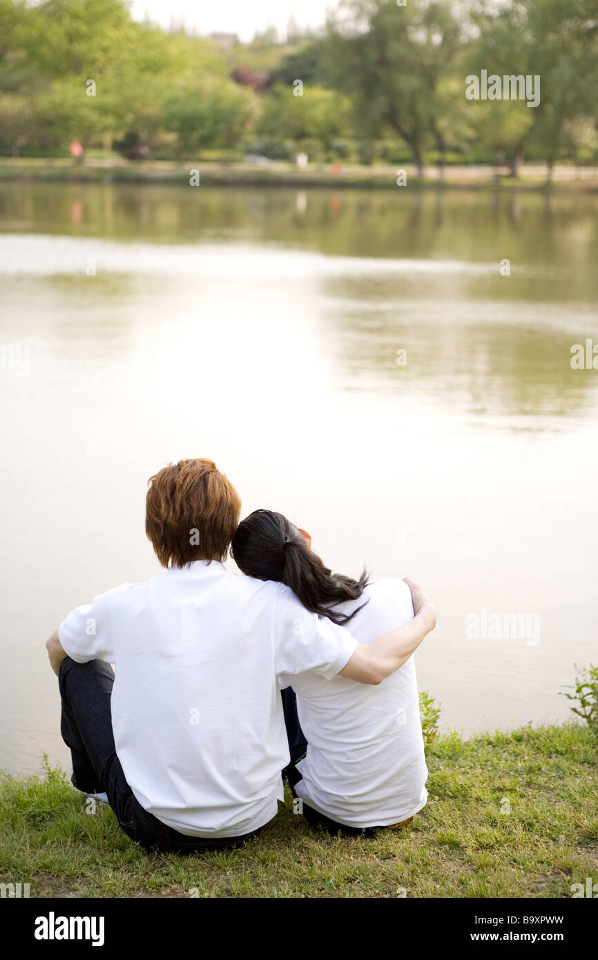 Young couple sitting on lawn by river Stock Photo - Alamy