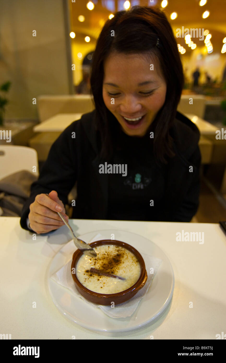 Asian tourist Enjoying Rice Pudding in Seville Spain Stock Photo