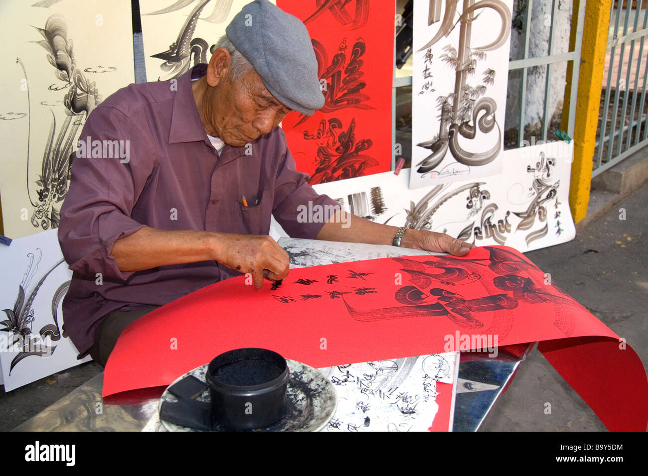 Vietnamese man drawing Chinese characters for good luck at the Giac Lam Pagoda Buddhist temple in Ho Chi Minh City Vietnam Stock Photo