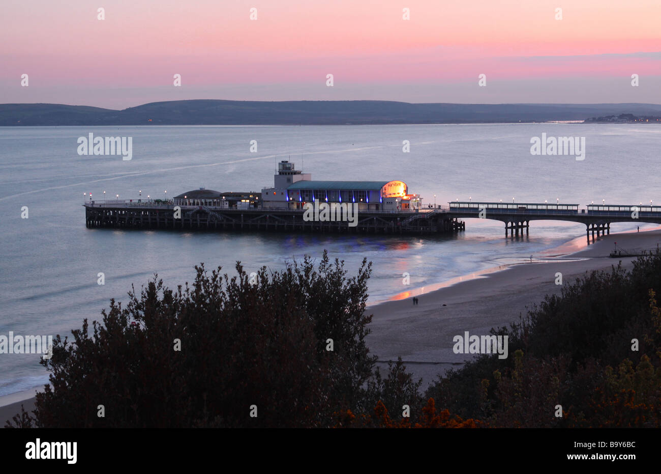 Bournemouth Pier at sunset from the cliff side through trees Stock Photo