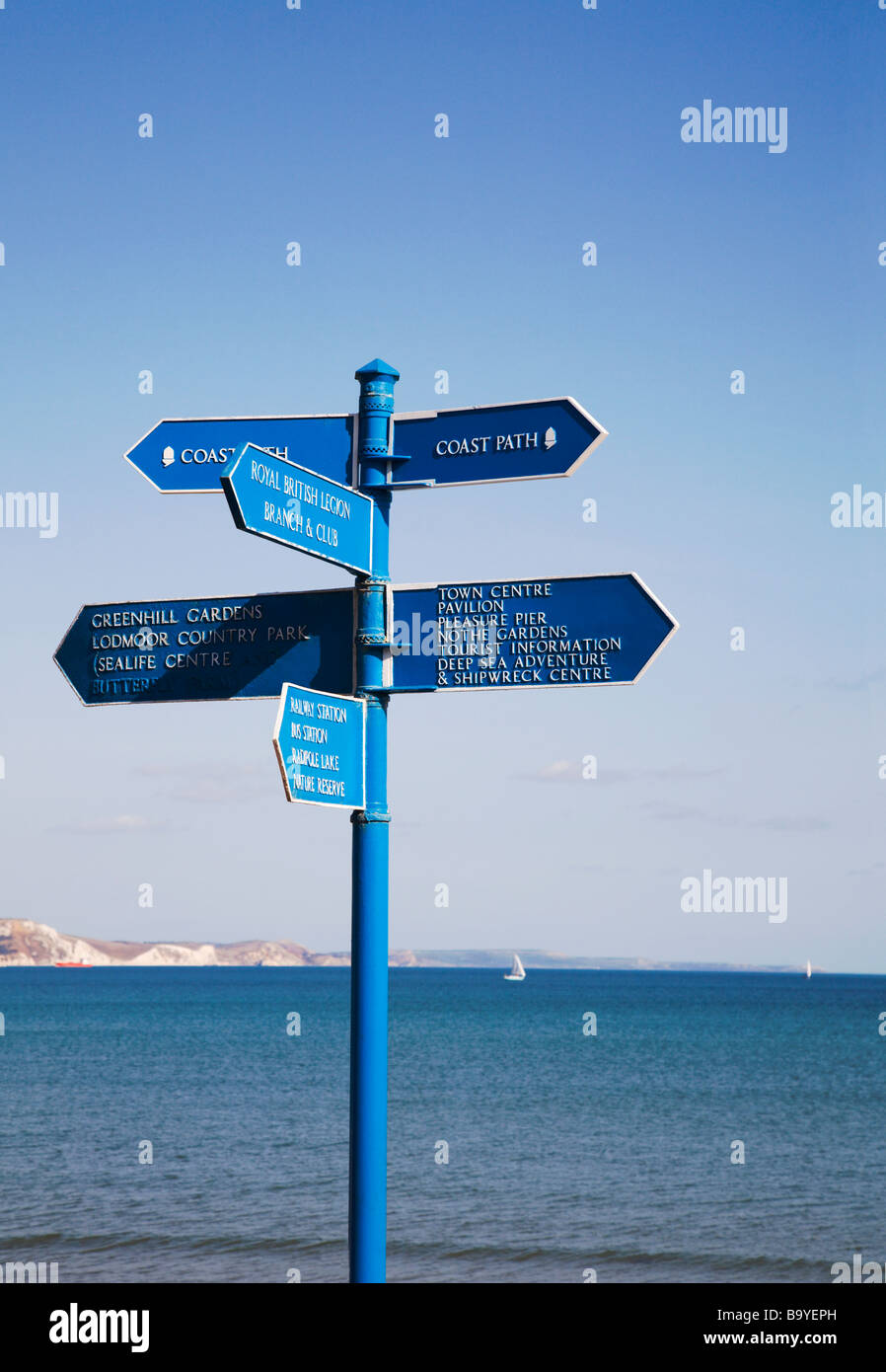 Direction signpost on Weymouth seafront, pointing to visitor attractions. Dorset. UK. View across Weymouth bay. Stock Photo
