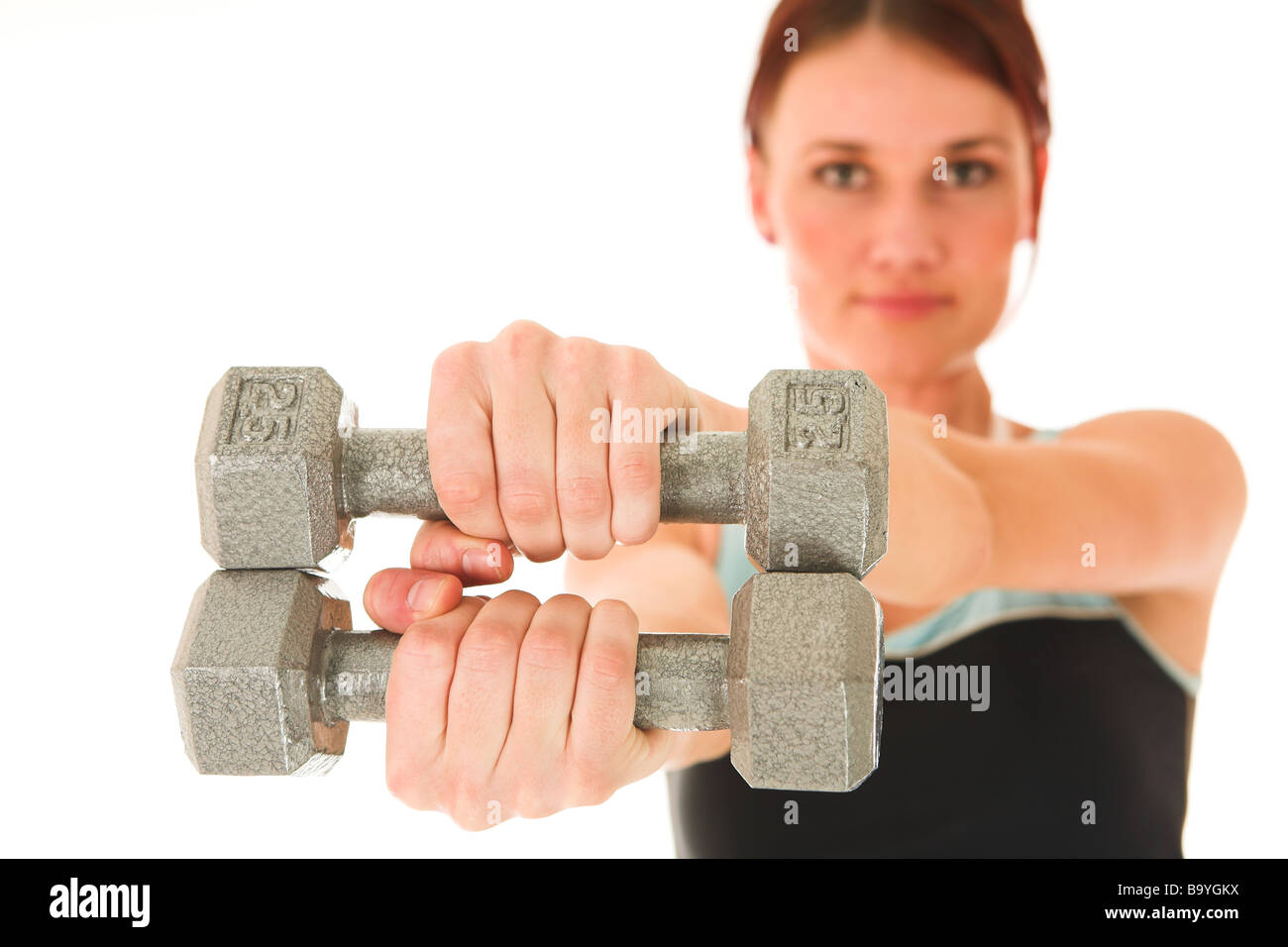 A woman in gym clothes holding weights out in front of her Shallow DOF