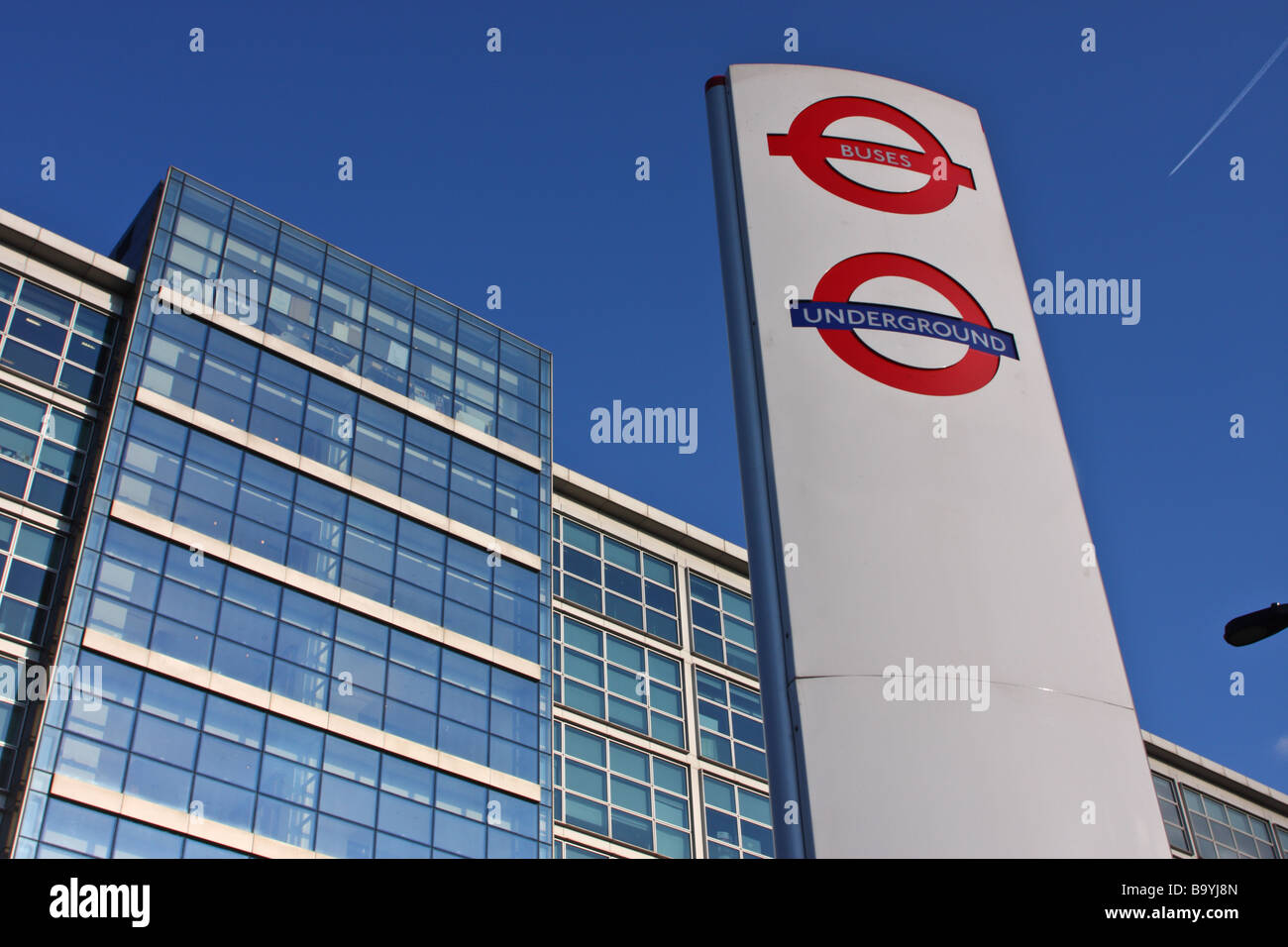 Bus stop and tube sign with office building in the background outside