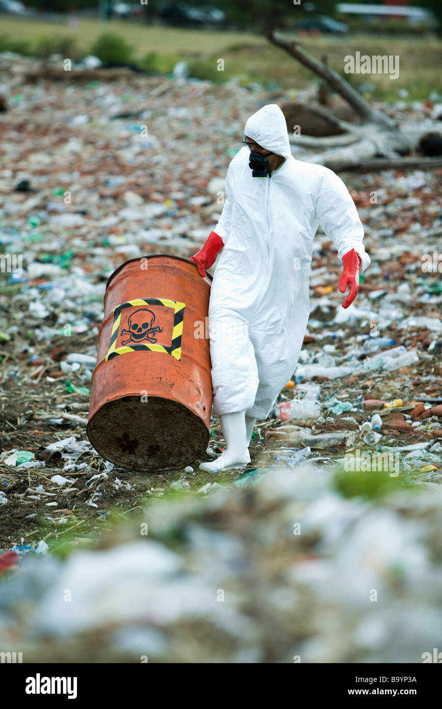 Person in protective suit carrying barrel of hazardous waste Stock Photo