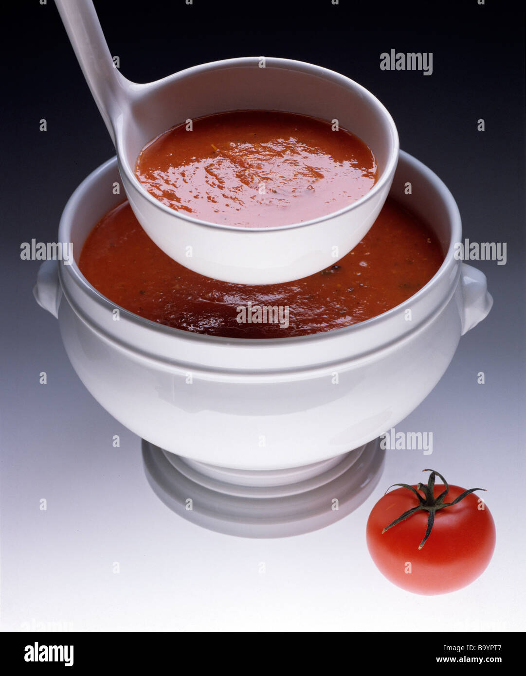 tomato soup in white china terrine with white china ladle and single