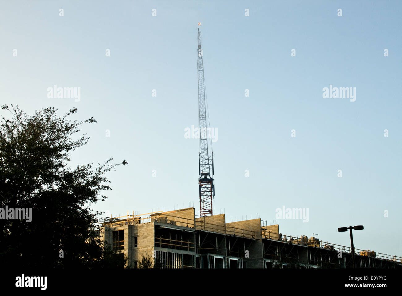 Large construction crane looming over a building on a clear day in Florida Stock Photo