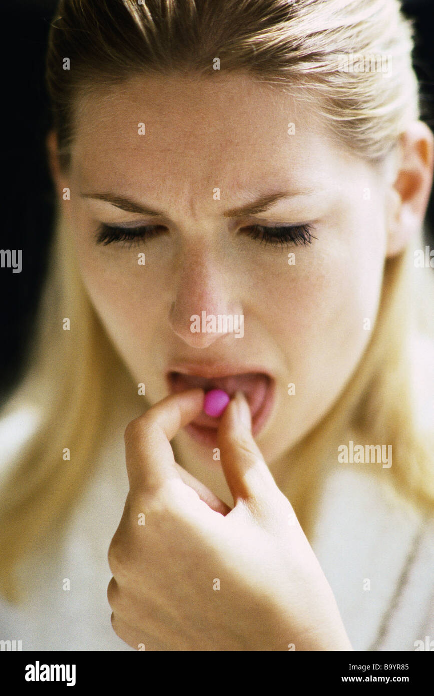 Woman placing pill on tongue Stock Photo