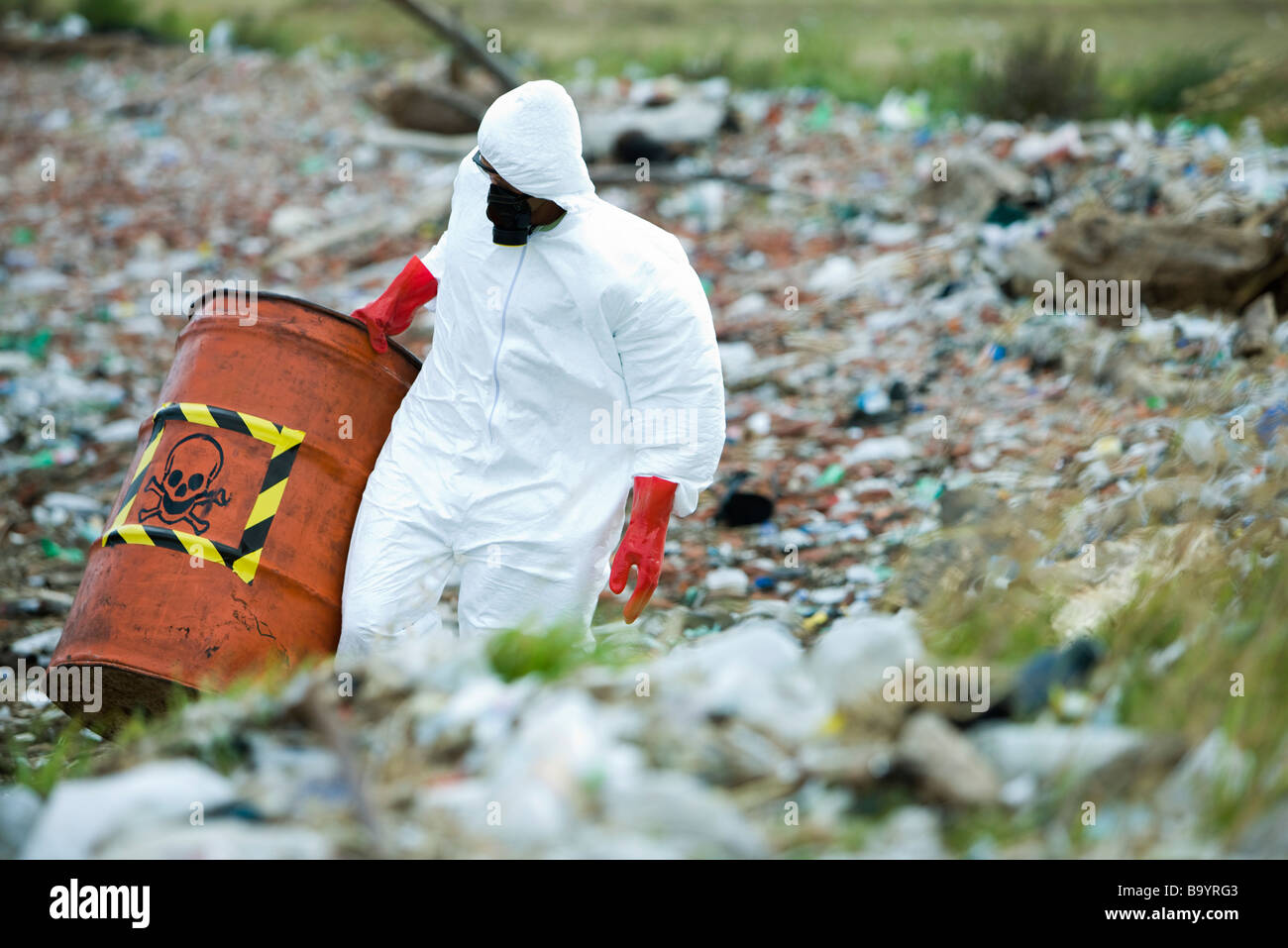 Person in protective suit carrying barrel of hazardous waste Stock Photo
