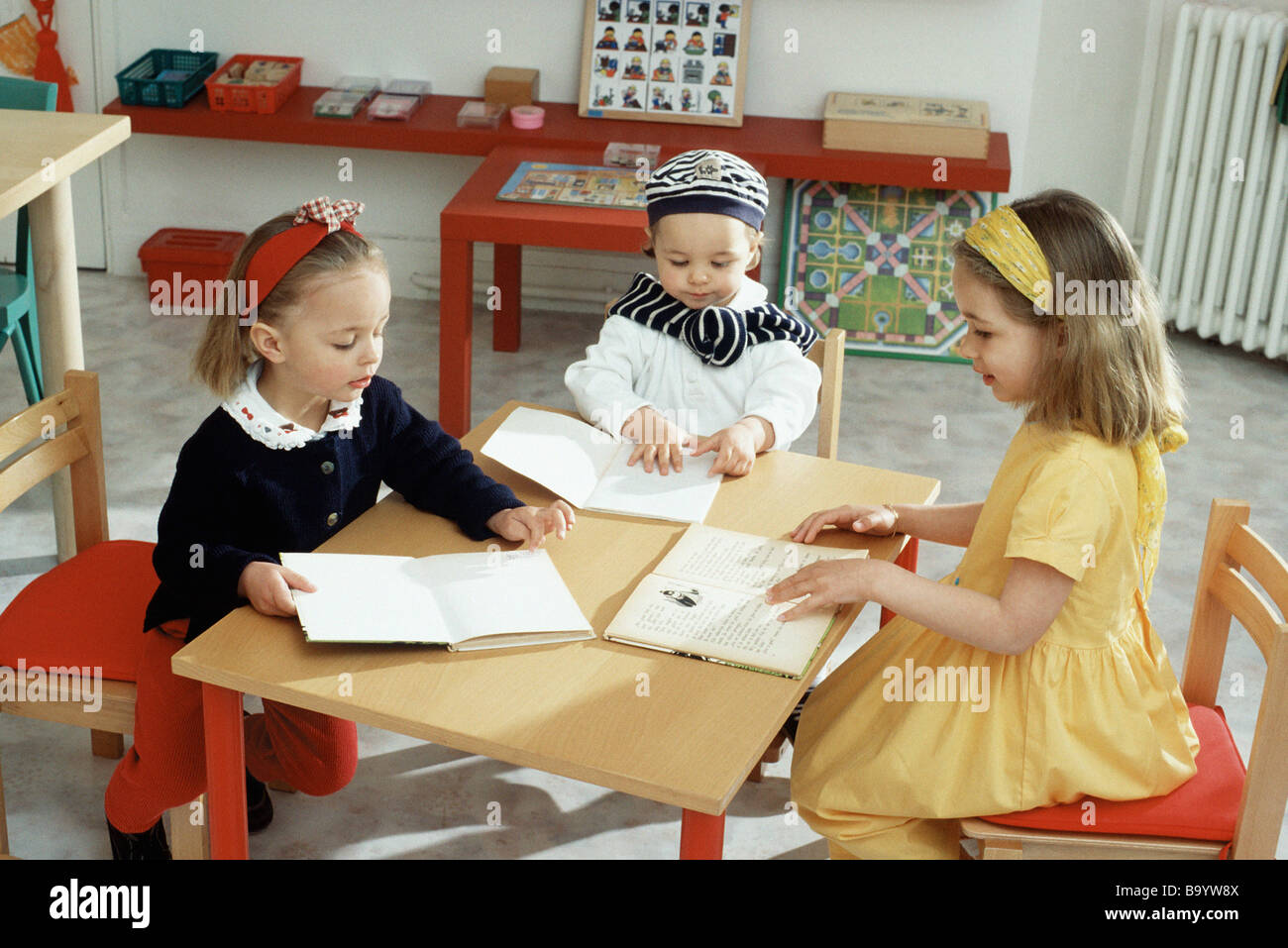 Children sitting around table with books Stock Photo Alamy