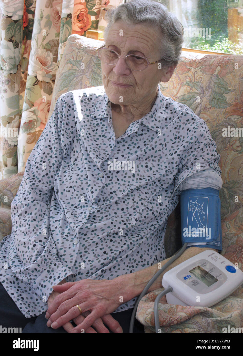 woman checking her blood pressure at home between visiting her gp Stock Photo