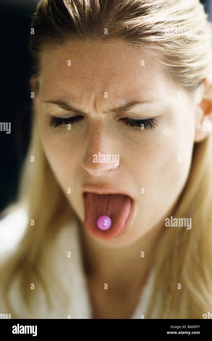 Woman sticking out tongue, showing pill Stock Photo