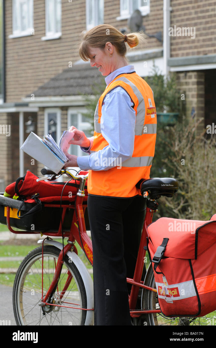 Royal Mail postwoman sorting letters on her round Stock Photo Alamy