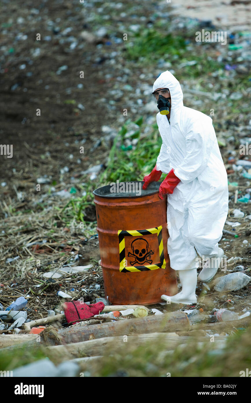 Person in protective suit carrying barrel of hazardous waste Stock Photo