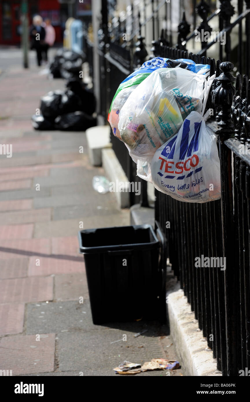 Plastic shopping bags filled with rubbish hung out on railings waiting