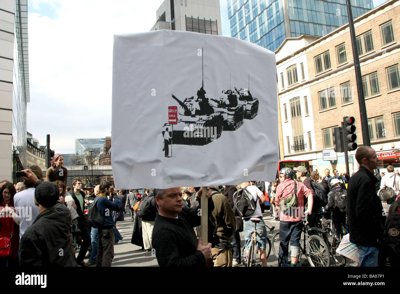 Banksy holds onto traffic light at G20 demonstration in London grafitti artist Stock Photo