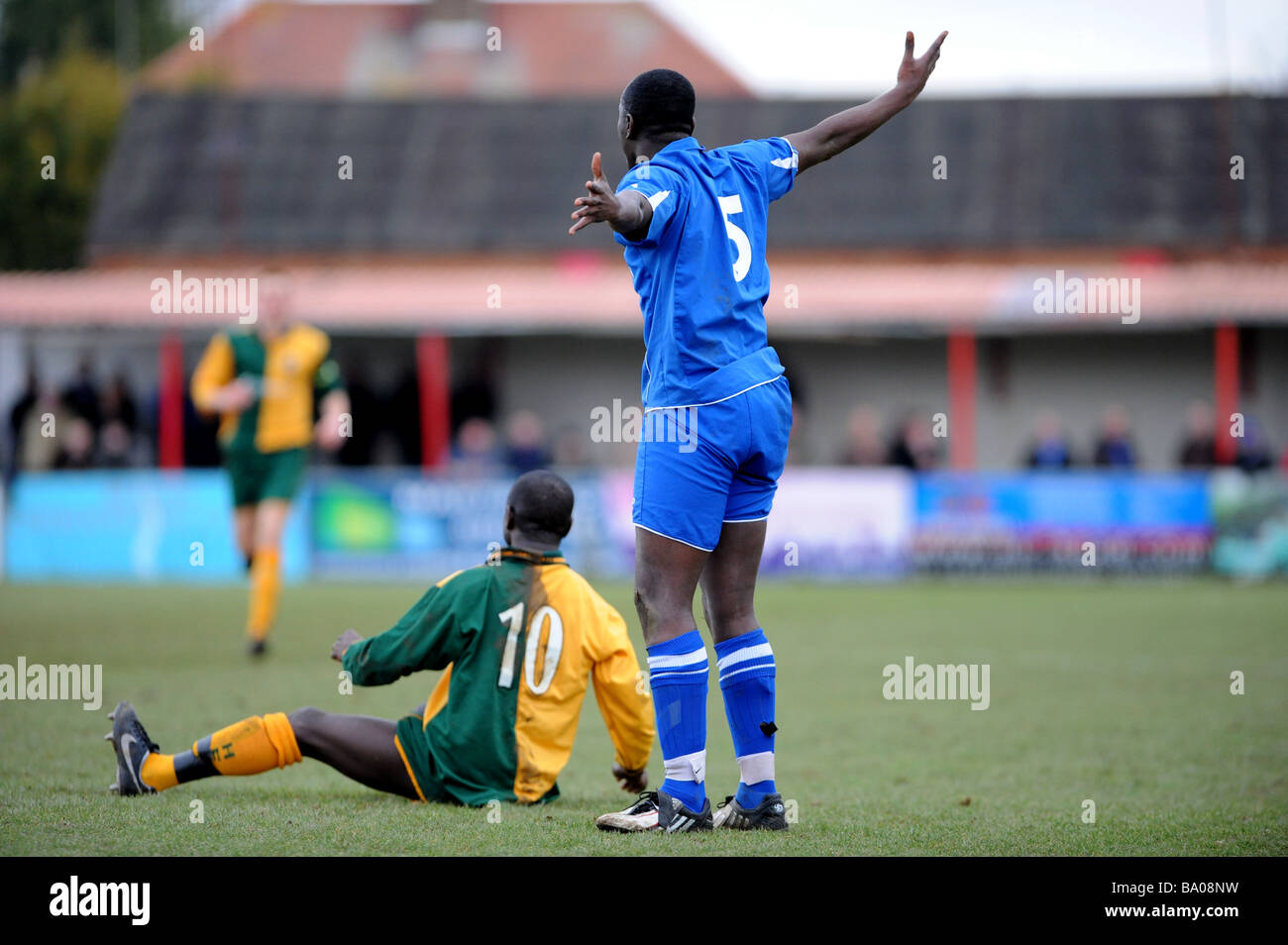 A footballer protests his innocence after another player is left on the ground after a tackle Stock Photo