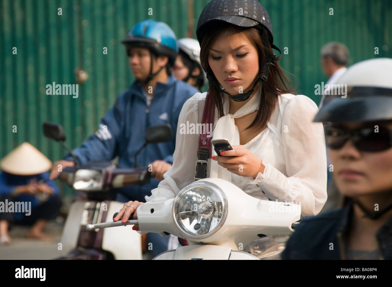 woman talking on her phone while riding a motorbike in Hanoi Vietnam Stock Photo