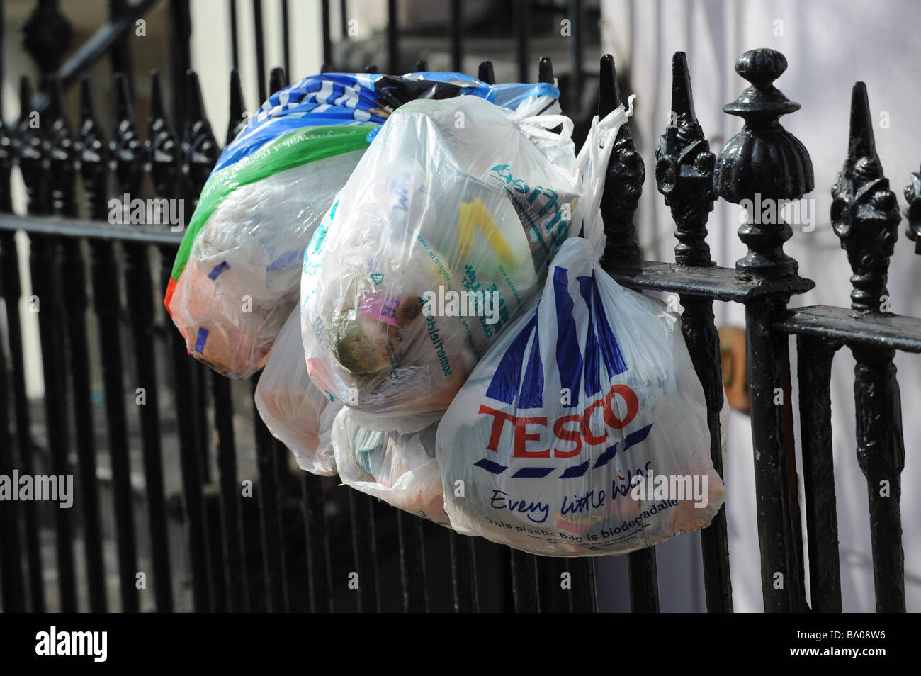Plastic shopping bags filled with rubbish hung out on railings waiting