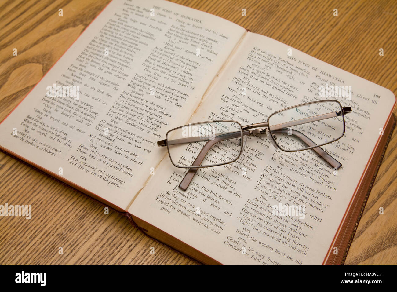 A pair of reading glasses resting on a book of Longfellow poems. Stock Photo