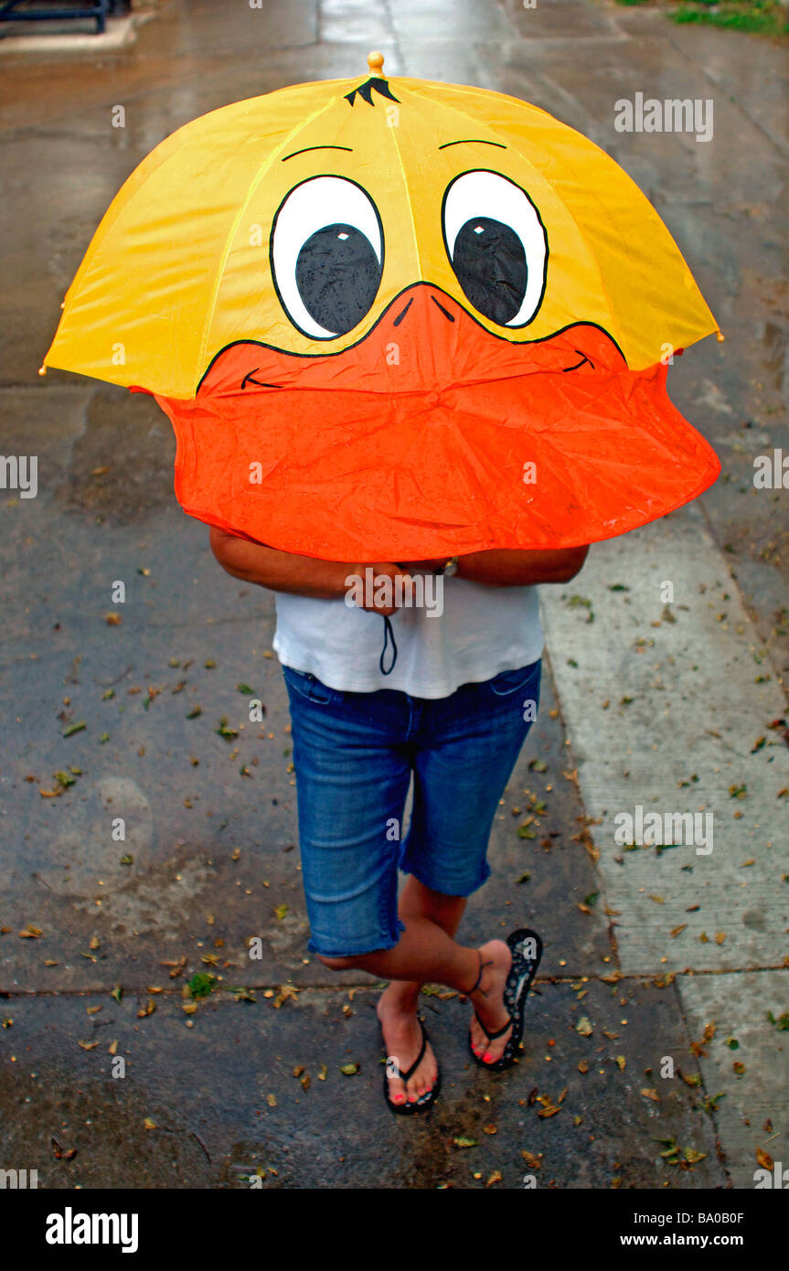 Humorous shot of lady and umbrella formed to the shape of a duck's head and face standing in the rain Stock Photo