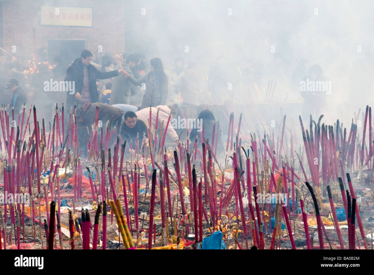 People making offerings of candles, incense sticks and burning paper