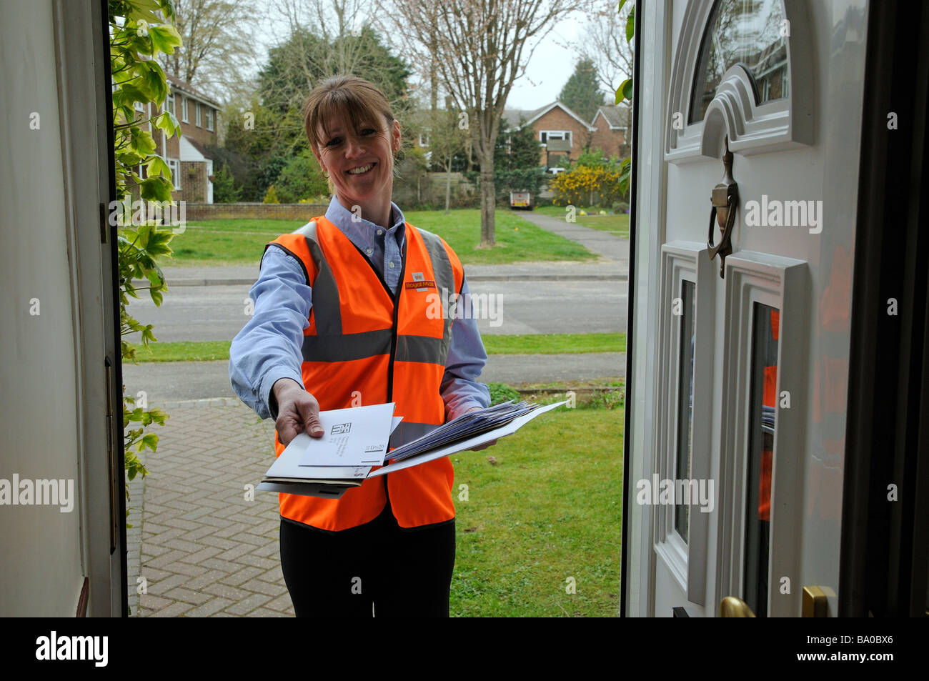 royal mail postwoman delivering mail to a customer Stock Photo - Alamy