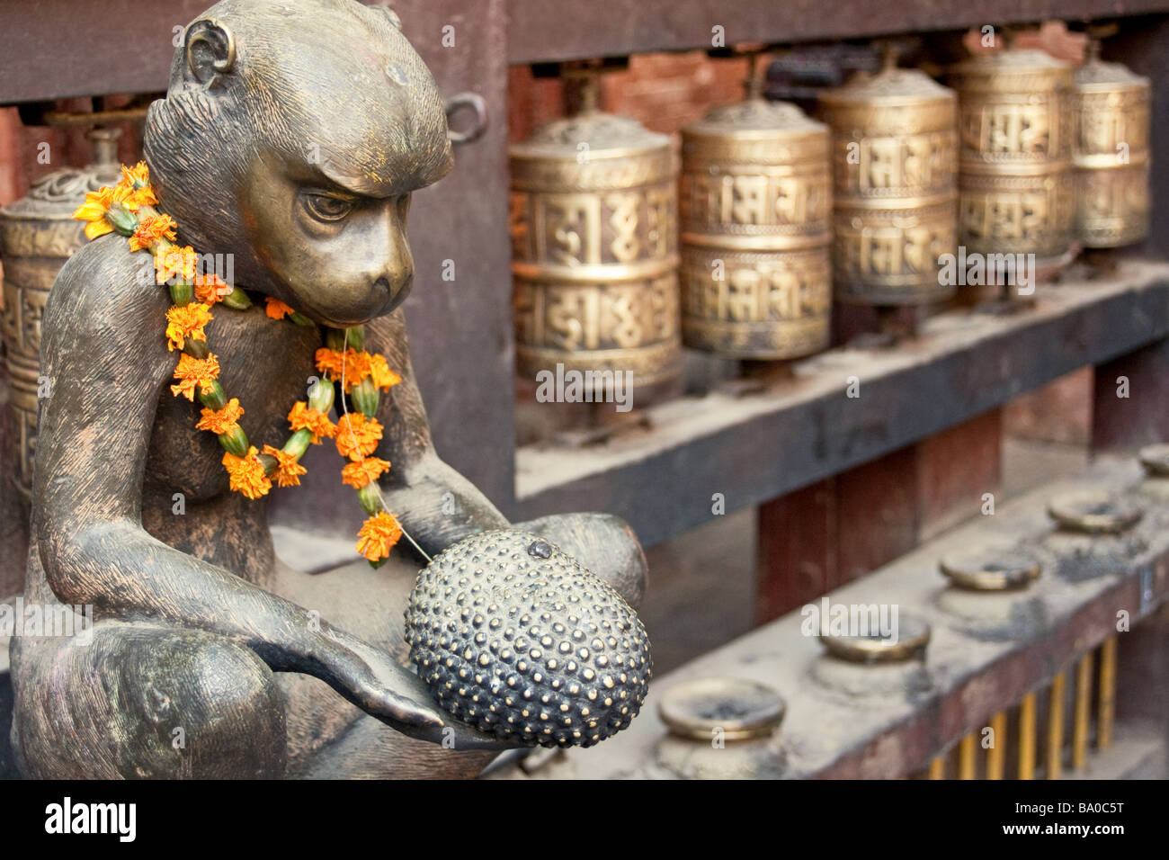 Brass monkey beside prayer wheels at the Golden Temple in Patan, Nepal Stock Photo