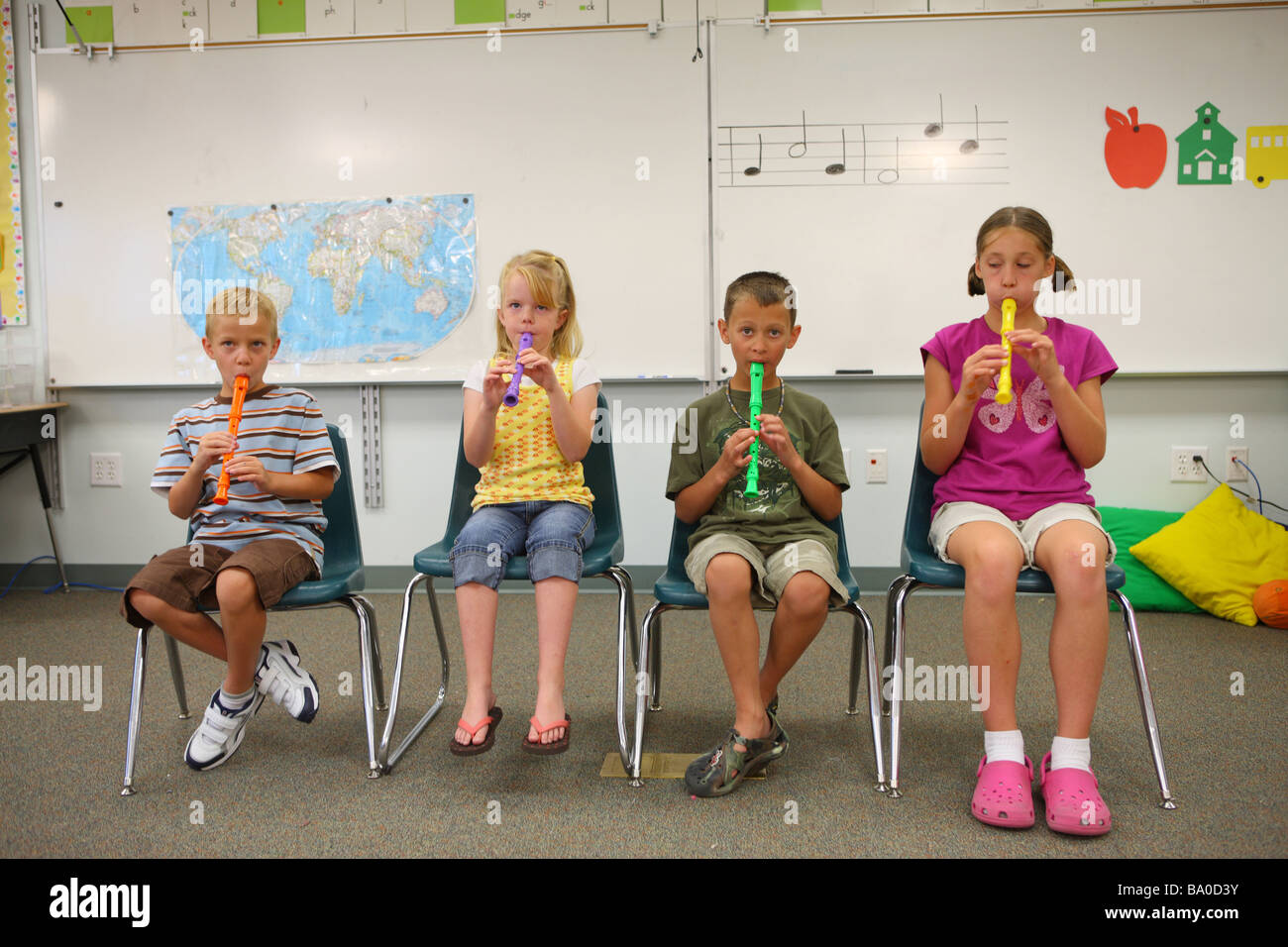 Four school children playing insturments in classroom Stock Photo
