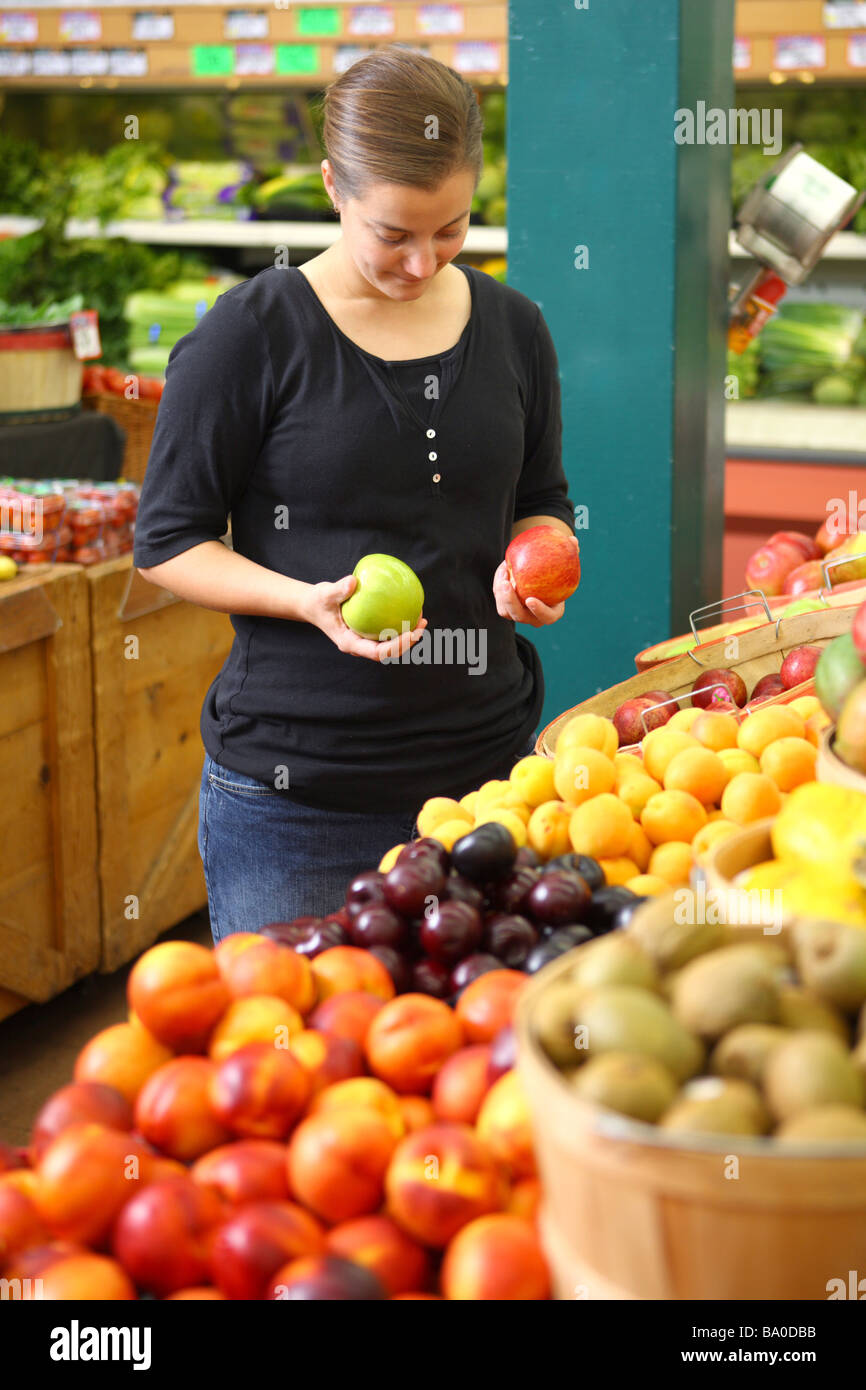 Woman at grocery store comparing two apples Stock Photo