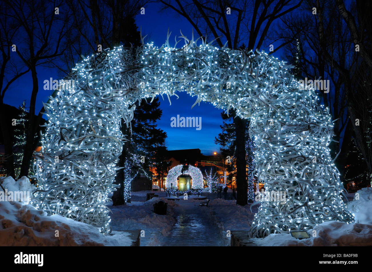 Brightly lit Elk antler arches in Jackson Wyoming USA town square in winter at twilight with indigo sky Stock Photo