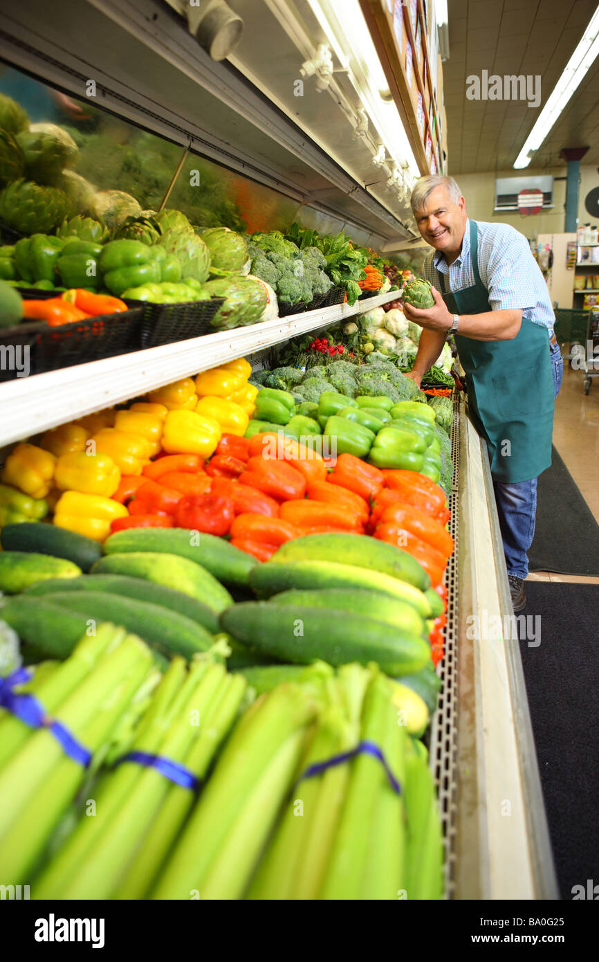 Senior man stocking produce at grocery store Stock Photo
