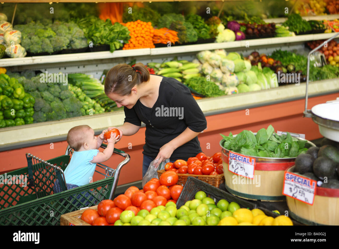 Mom and baby in grocery store picking out produce Stock Photo