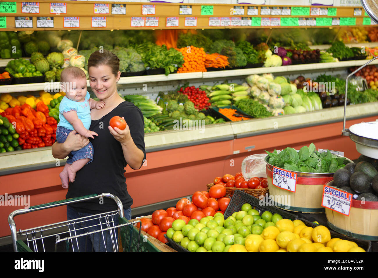 Mom and baby in grocery store picking out produce Stock Photo