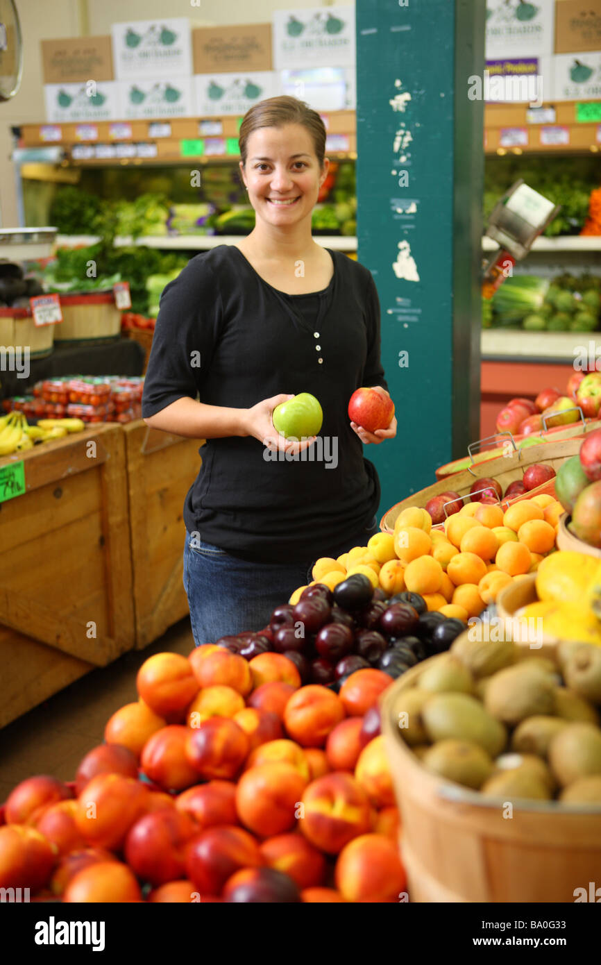 Woman in grocery store with two different apples Stock Photo