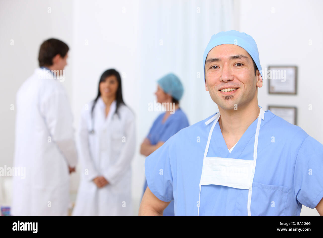 Portrait of surgeon with other medical personnel in background Stock Photo