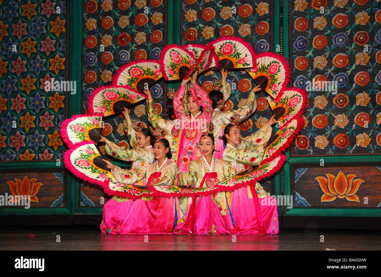 A group of Korean dancers performing traditional folk dance on stage in a formation that resembles shape of a flower Stock Photo
