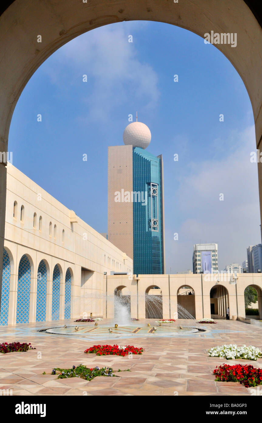 Abu Dhabi Cultural Foundation paved courtyard and fountain with red petunia flowers framed by arch Stock Photo