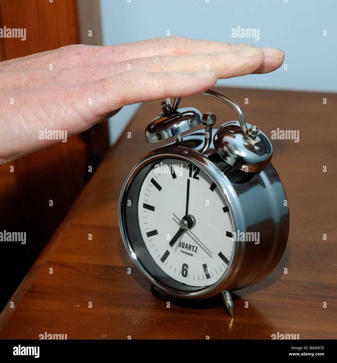 Alarm clock womans hand switching an early morning alarm call off Stock Photo