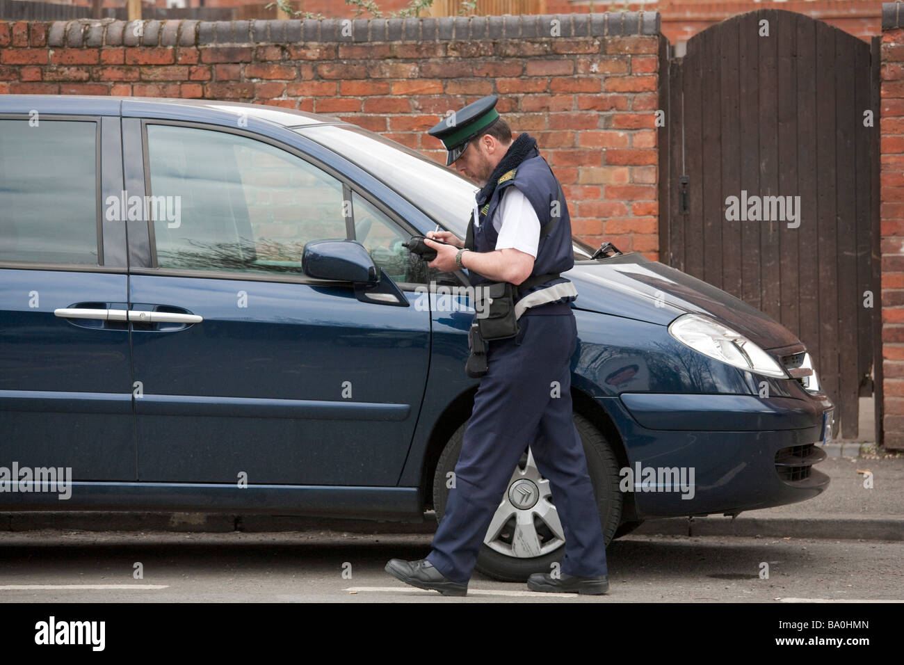 UK traffic warden / parking attendant inspects and notes details of a
