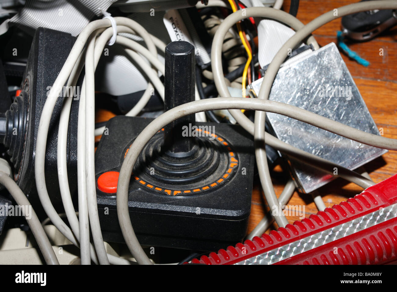 Old Atari simple joystick with one button amid pile of wires and other electronics junk. Stock Photo